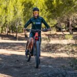 a man riding a bicycle on a dirt path in the woods